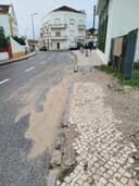 Passeio danificado com buraco, gravilha e areia solta.